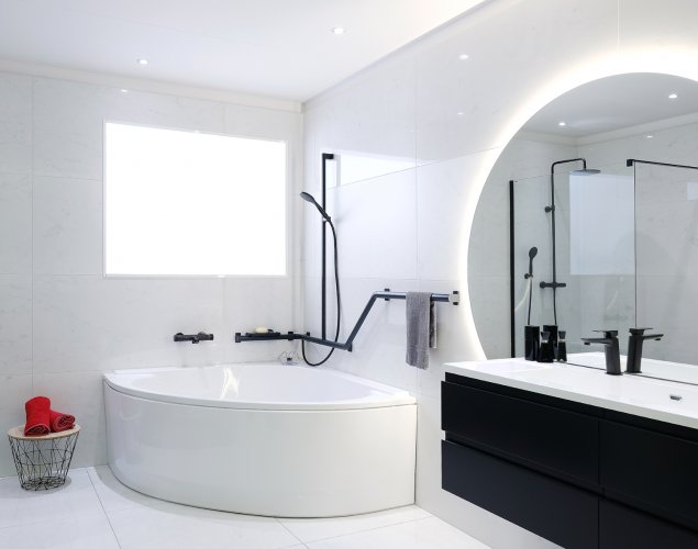 Salle de bain PMR avec baignoire d'angle, carrelage blanc au sol.