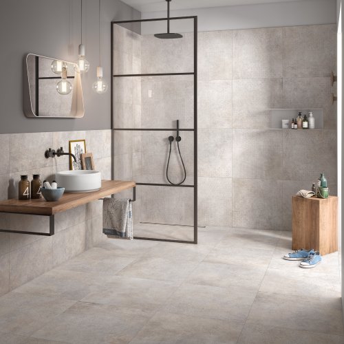 Salle de bain avec douche à l'italienne, carrelage sol et murs imitation pierre naturelle beige.